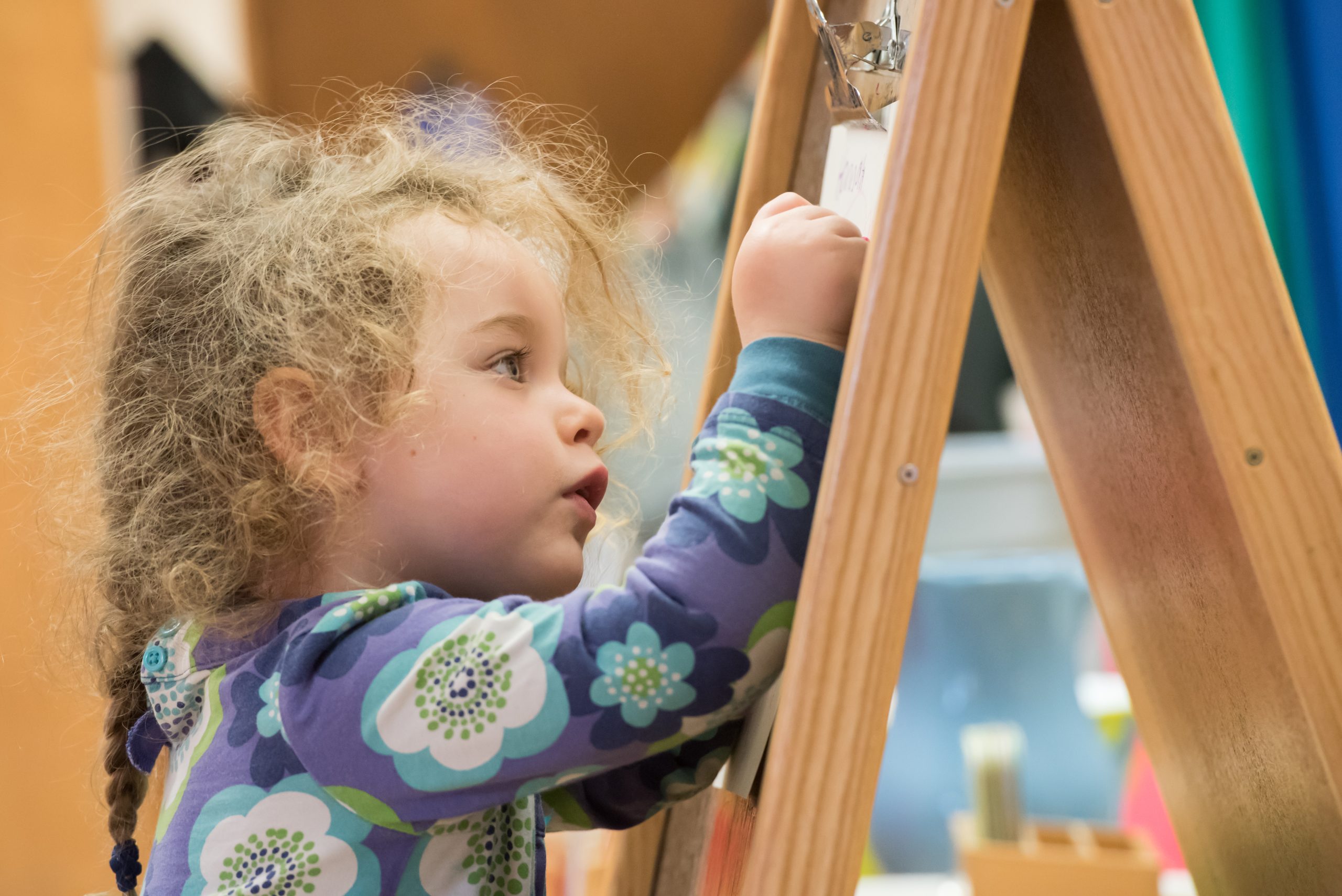 A Children's House student drawing on an easle