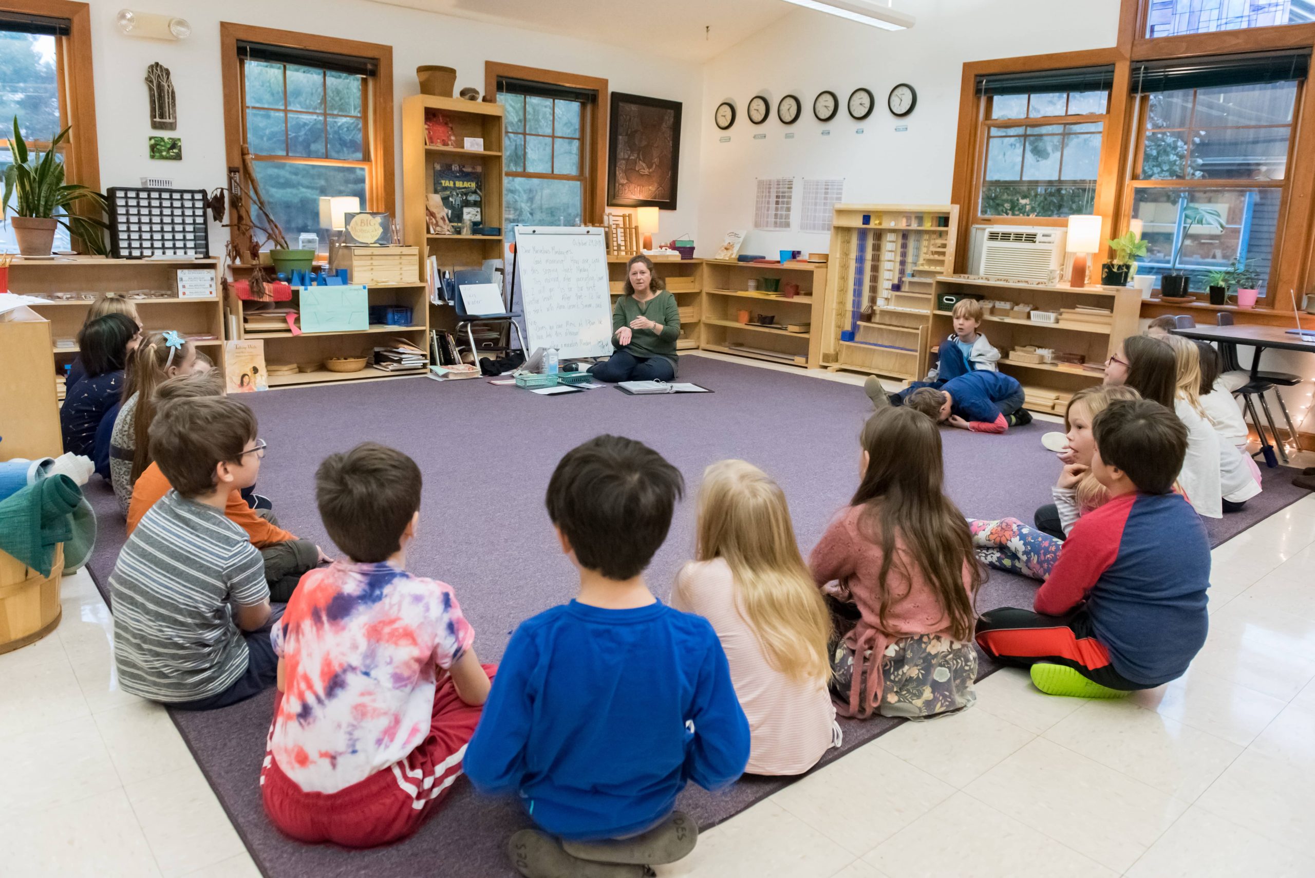 Lower Elementary students are gathered around for a lesson