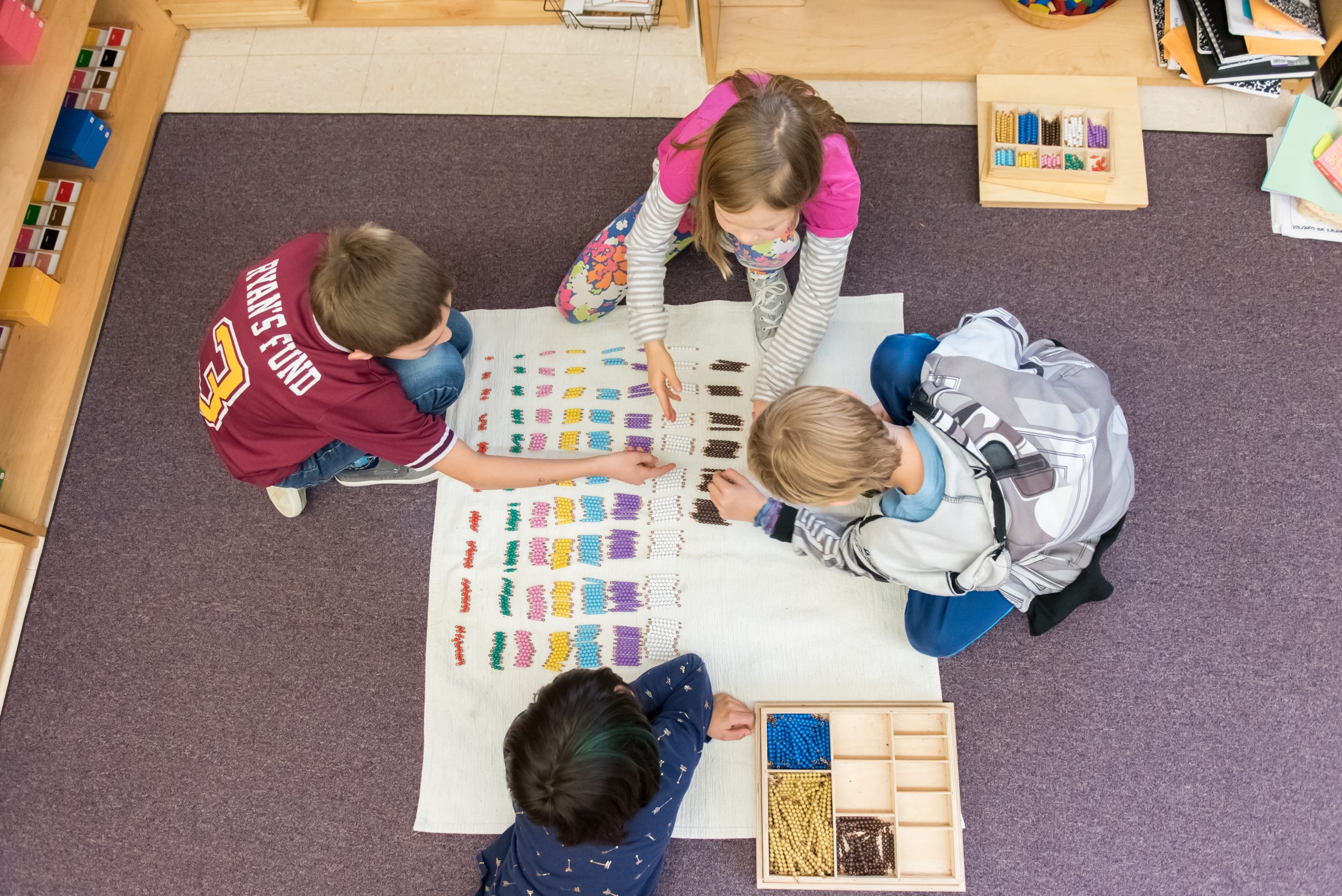 Three Montessori Lower El students work together on a math lesson