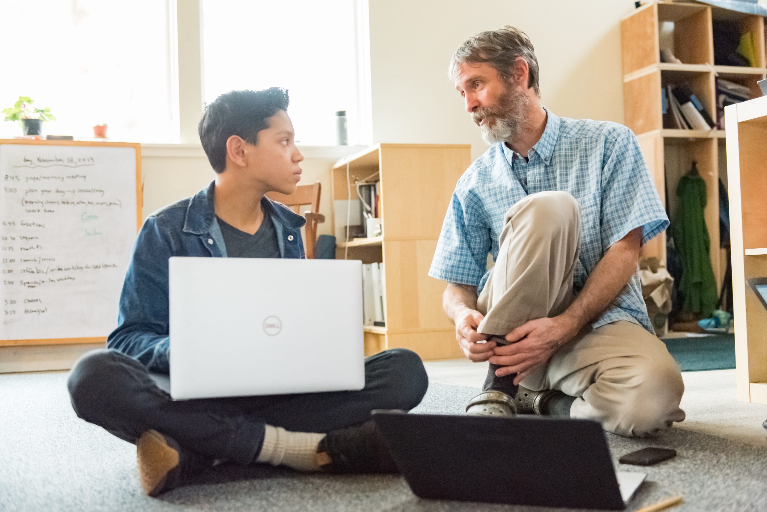 A Montessori Middle School student works with their teacher on an assignment