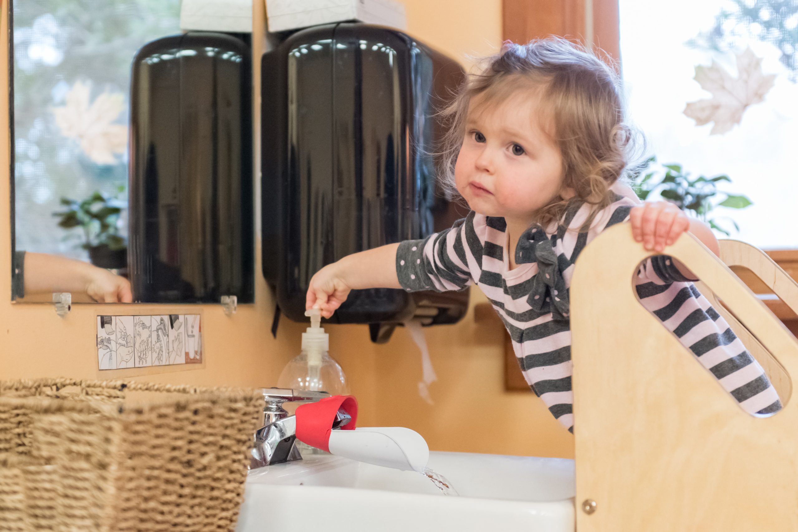 A Montessori toddler at the handwashing station